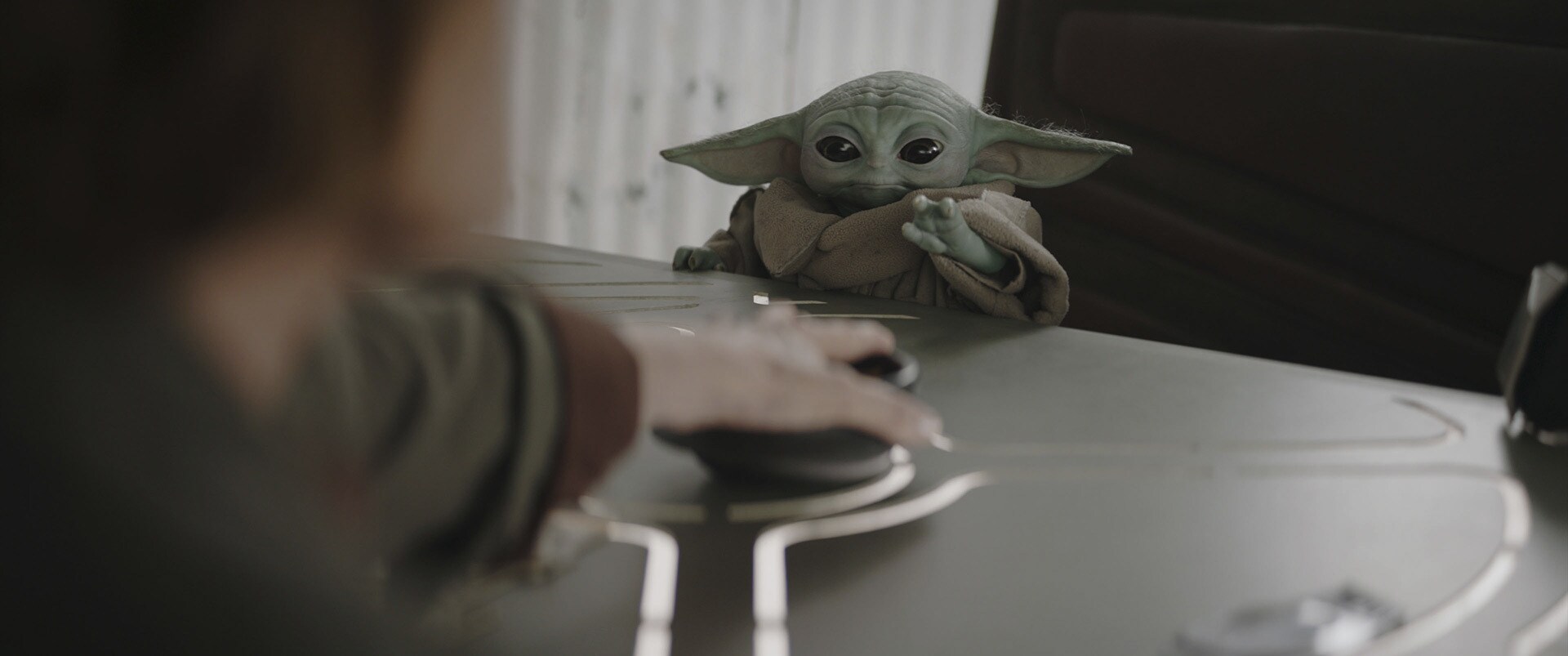 Grogu reaches across a table with the Force.